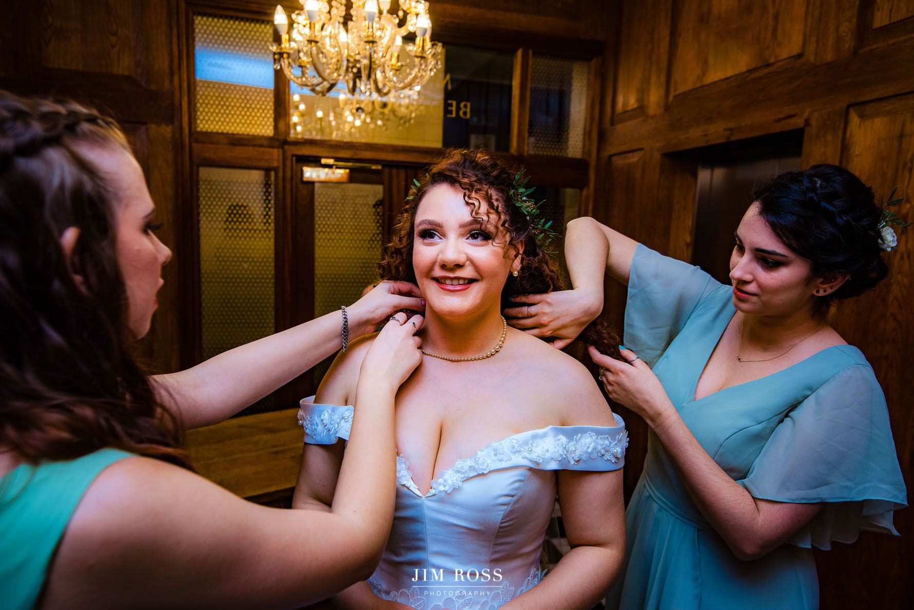 bridesmaids help with bride's necklace