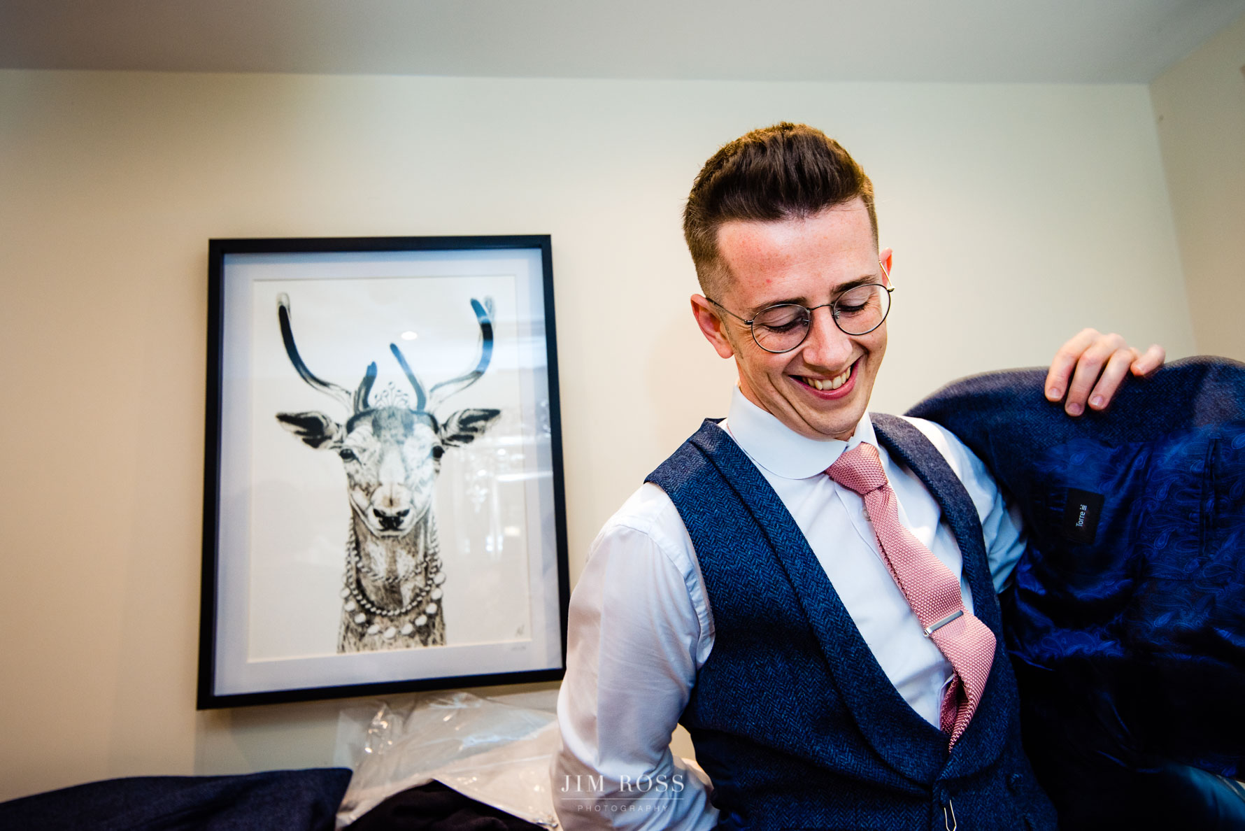 groom puts on jacket in front of stag picture