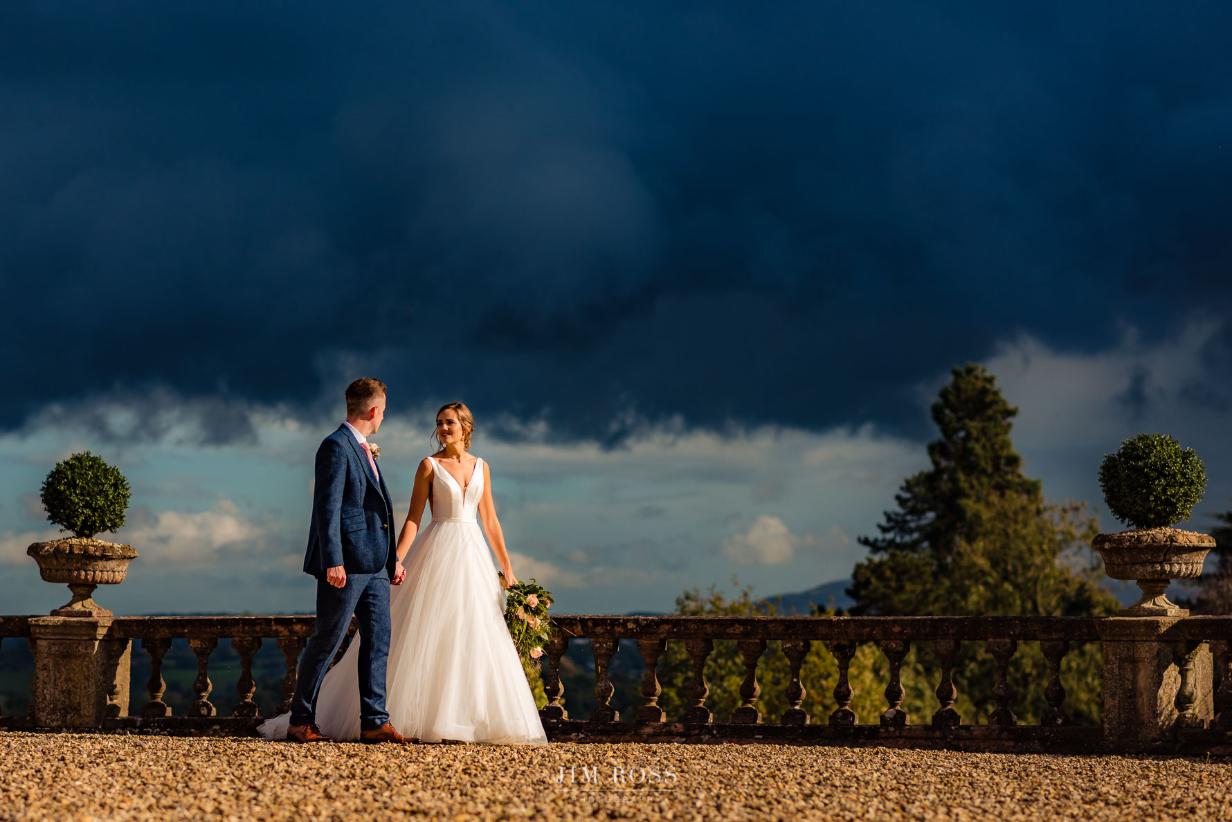 newlyweds walk in beautiful light with storm clouds in distance