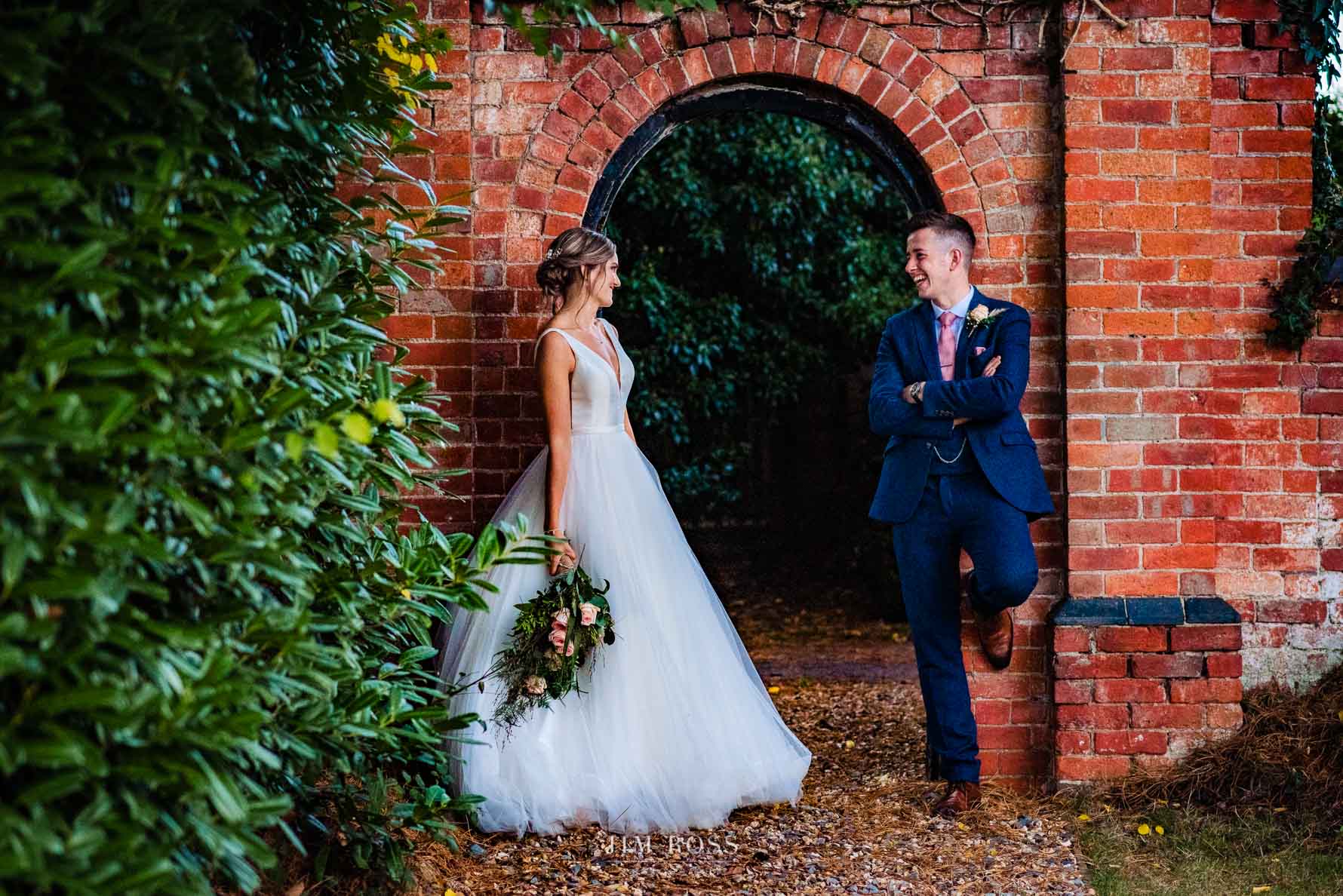 bride and groom posing at romantic arch