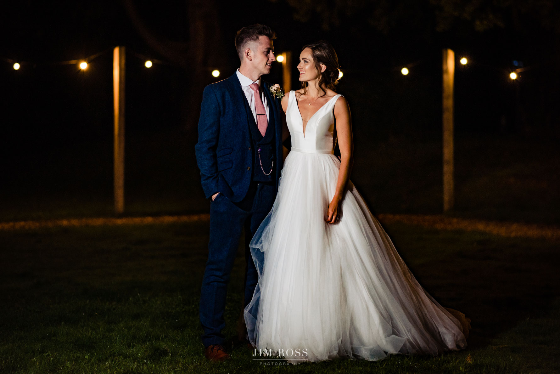 newlywed night portrait with festoon lights in background