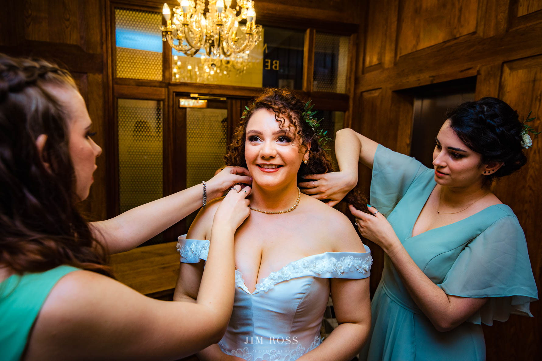 bridesmaids adjust bride's necklace