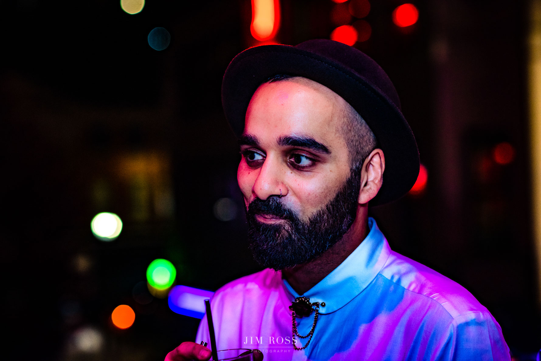 wedding guest in hat with city lights behind