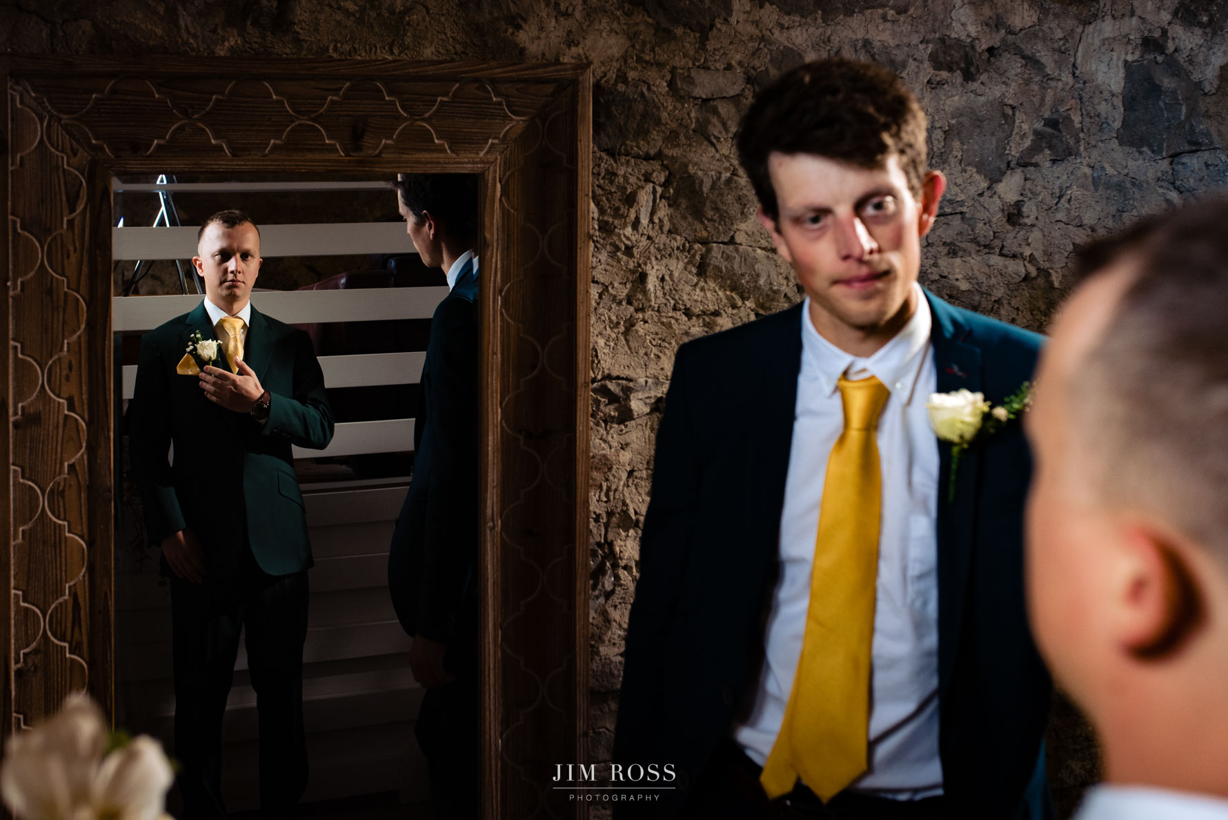 mirror shot of groom and brother with button holes