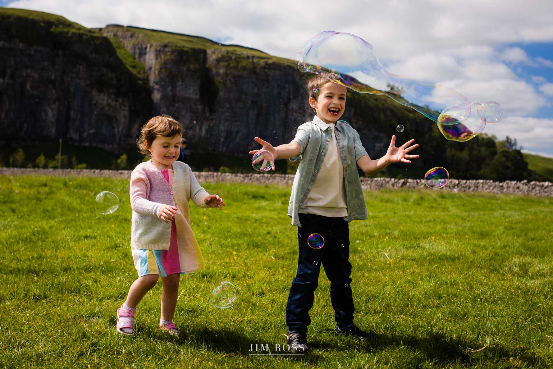 kids chasing bubbles with Yorkshire crags behind
