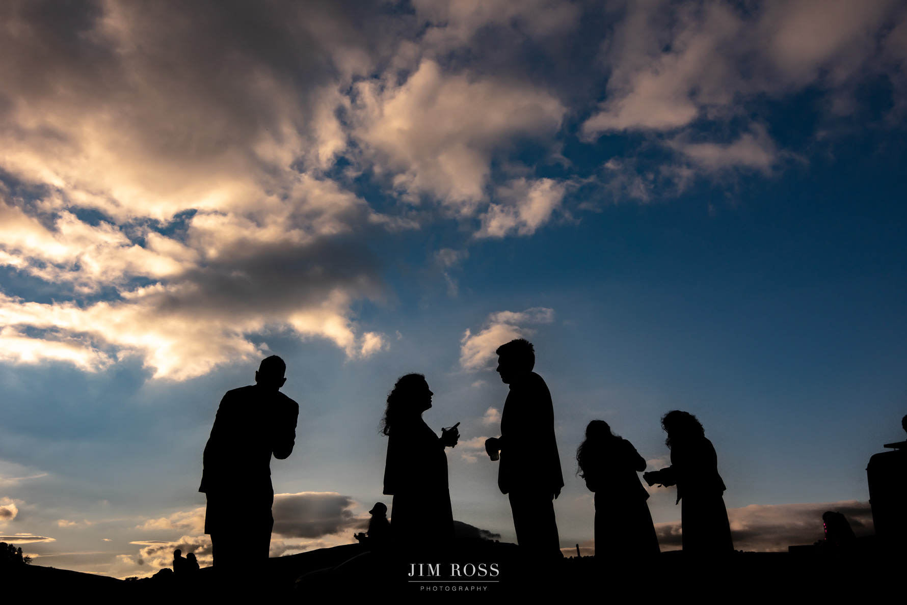 Silhouette of wedding guests in tipi field