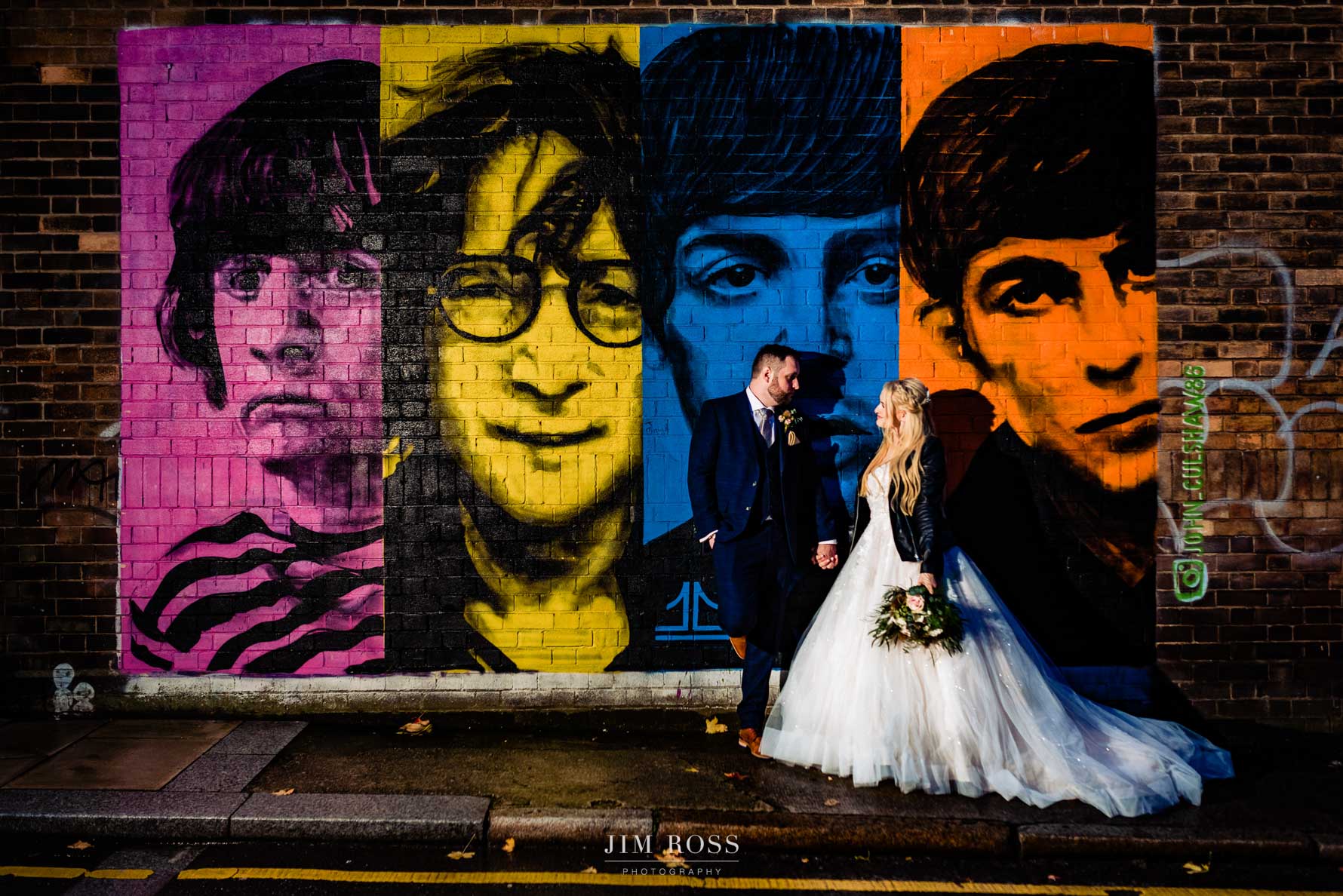 Newlyweds flash portrait in front of Beatles mural